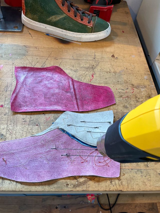 A heat gun setting glue on the backs of
a maroon leather high-top lining
and frankensteined low-high
with random stitches showing through.